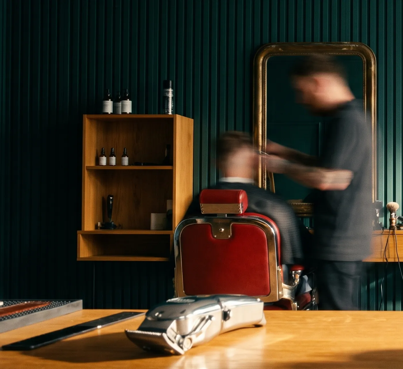 Barbeři stříhají zákazníky u zrcadel v barbershopu